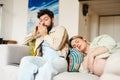 Man talking on cellphone while his pregnant wife sleeping on couch