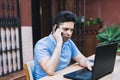 Man talking on his mobile phone while trading cryptocurrencies with the laptop