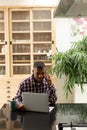 Man talking on mobile phone while using laptop on worktop in kitchen Royalty Free Stock Photo