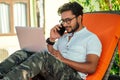 Man talking on the phone india summer holidays.stylish young indian male freelancer working with laptop freelance Royalty Free Stock Photo