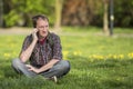 man talking on phone sitting on green grass in the Park. Royalty Free Stock Photo