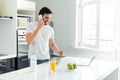 Man talking on smartphone near laptop and breakfast on kitchen table Royalty Free Stock Photo