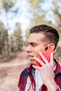 Man talking on smartphone on path between trees