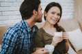 Man Talking Smiling Woman with Cup on Brown Sofa.