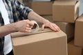 Man taping cardboard box indoors, closeup. Moving day