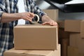 Man taping cardboard box indoors, closeup. Moving day