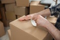 Man taping cardboard box indoors, closeup. Moving day