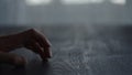 Man tapping fingers on black oak table with back light