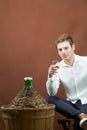 Man tasting a glass of white wine near a carboy Royalty Free Stock Photo