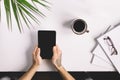 Man with tattoo holding tablet on office desk table with , supplies, flower and cup of coffee. Top view Royalty Free Stock Photo