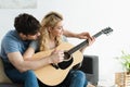 Man teaching blonde happy woman playing acoustic guitar at home Royalty Free Stock Photo