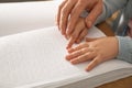 Man teaching child to read book written in Braille