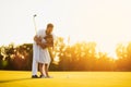 A man is teaching his daughter to play golf. He guides her, the girl is getting ready to make her first punch in golf Royalty Free Stock Photo