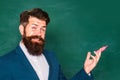 Man teaching near chalkboard in classroom. Portrait of a funny teacher or professor near blackboard. Thinking serious Royalty Free Stock Photo