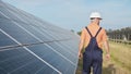 Man technician in hard hat walks on new ecological solar construction outdoors. Farm of solar panels. Maintenance