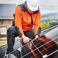 Man technician mounting photovoltaic solar panels on roof of house with help of hex key. Royalty Free Stock Photo