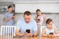 Man and teenage daughter engrossed in smartphones at table in home kitchen Royalty Free Stock Photo