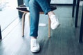 Man teenager legs wearing white sneakers sitting relaxing at home. teenage leisure lifestyle