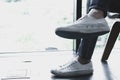 Man teenager legs wearing white sneakers sitting relaxing at home. teenage leisure lifestyle