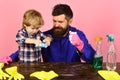 Man with tense face and child cleaning table with sponges