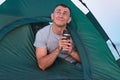 Man in tent drinks from tourist mug. Morning hike. Camping Royalty Free Stock Photo