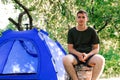 Man tent summer. Defocus young man tourist sitting in touristic tent at the beach. Camping, tourism and travel concept Royalty Free Stock Photo