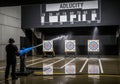 Man tests water cannon accuracy on targets in dark shooting range Royalty Free Stock Photo