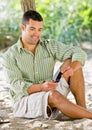 Man text messaging on cell phone at beach