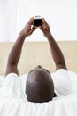 Man text messaging on mobile phone in bedroom Royalty Free Stock Photo