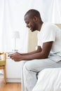 Man text messaging on mobile phone in bedroom Royalty Free Stock Photo