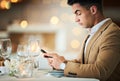 Man, texting and phone at restaurant table for food, night and waiting for valentines day date. Young male, smartphone