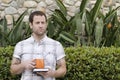 Man thinking about the future holding a book and orange cup outside.