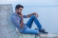 Man thinking sitting on a concrete bridge above the sea