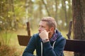 Man thinking moody portrait, sitting at autumn park