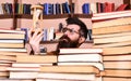 Man on thoughtful face holds hourglass while studying, bookshelves on background. Man, scientist in glasses looks at Royalty Free Stock Photo