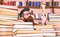 Man on thoughtful face holds hourglass while studying, bookshelves on background. Man, scientist in glasses looks at Royalty Free Stock Photo