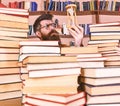 Man on thoughtful face holds hourglass while studying, bookshelves on background. Teacher or student with beard studying Royalty Free Stock Photo