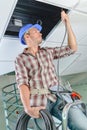 Man threading cable into space above suspended ceiling Royalty Free Stock Photo