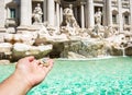 Man is throwing coin at Trevi Fountain for good luck