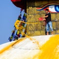 Man throwing orange paint on Boudhanath stupa Royalty Free Stock Photo