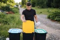 Man throwing out in recycling bin clean empty plastic container. Different colour of recycling bins