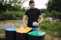 Man throwing out in recycling bin clean empty plastic container. Different colour of recycling bins