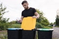 Man throwing out in recycling bin clean empty plastic container. Different colour of recycling bins