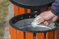 A man throws a bill into the trash can. Conceptual photo. Money supply inflation, financial crisis. Waste of money