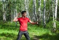 A man throws a knife at a target in the summer forest, side view. Throwing a knife