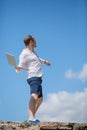 Man throws notebook against blue sky