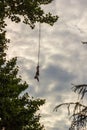 A man tied to a rope upside down doing bungee jump while holding an action camera Royalty Free Stock Photo