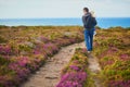 Man and toddler girl walking in heather meadows on Cape d`Erquy in Brittany, France