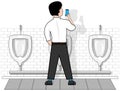 A man on an isolated white background in a toilet at the urinal, looks at the phone that holds in his hand.