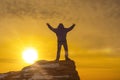 Man at the top of the mountain, holding up his hand, against the background of a dramatic sky in the sunset. Royalty Free Stock Photo